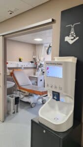 Smixin automatic handwashing station next to a hospital treatment bed