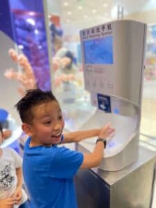 Child washing hands with a Smixin automatic system in a public venue