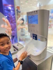 Child washing hands with a Smixin automatic system at a public event