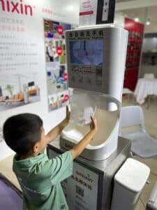 Child using a Smixin automatic handwashing station at an exhibition